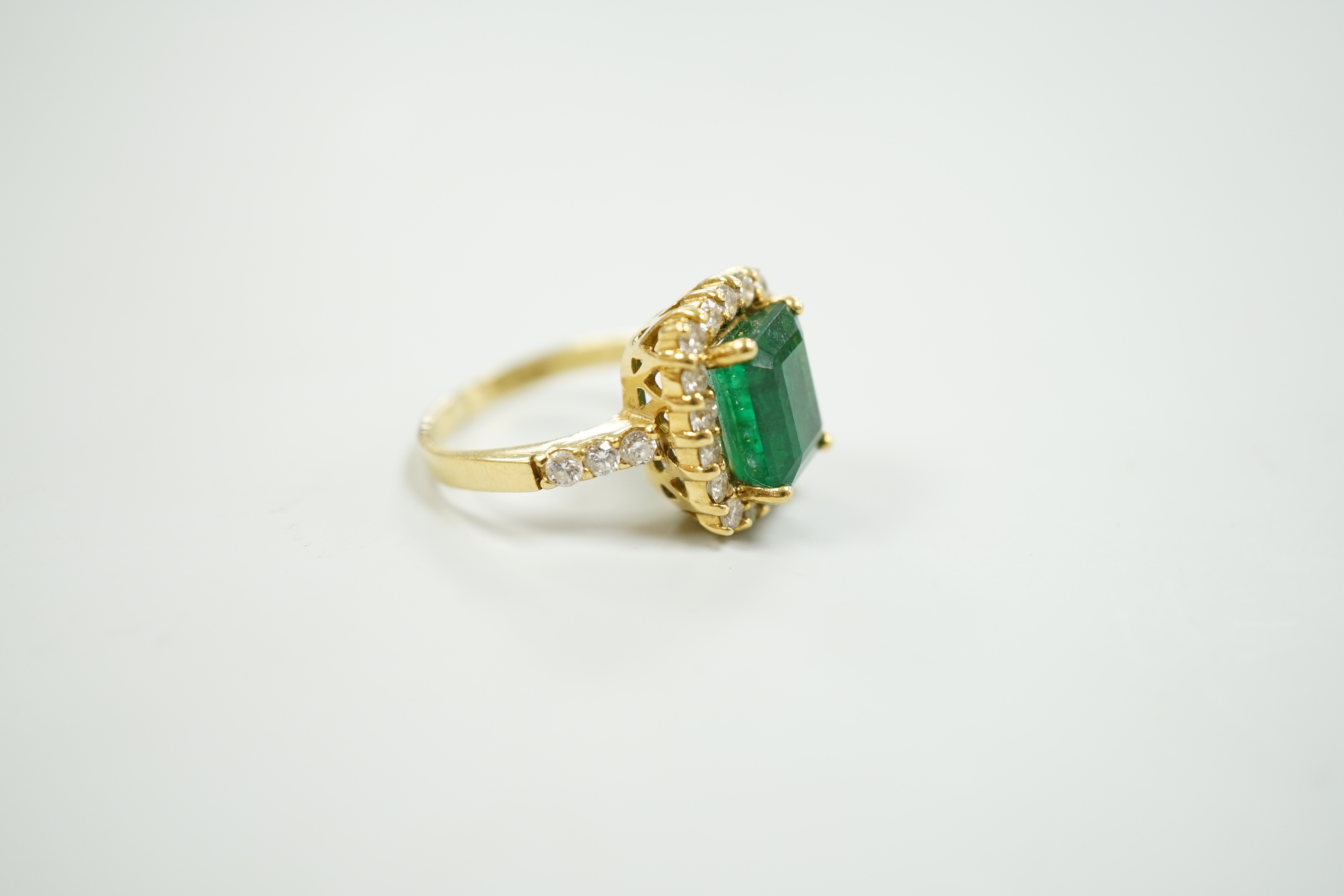 A modern 18ct gold and single stone emerald set dress ring, with diamond set border and shoulders, size L, gross weight 6.5 grams, with accompanying Beverley Hills Gemological Laboratory appraisal certificate date 18/11.